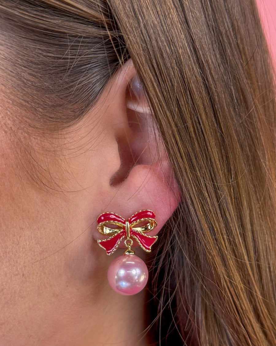lightweight pink enamel bow stud trimmed in gold with a dangling iridescent pearl finished with a comfort disc backing