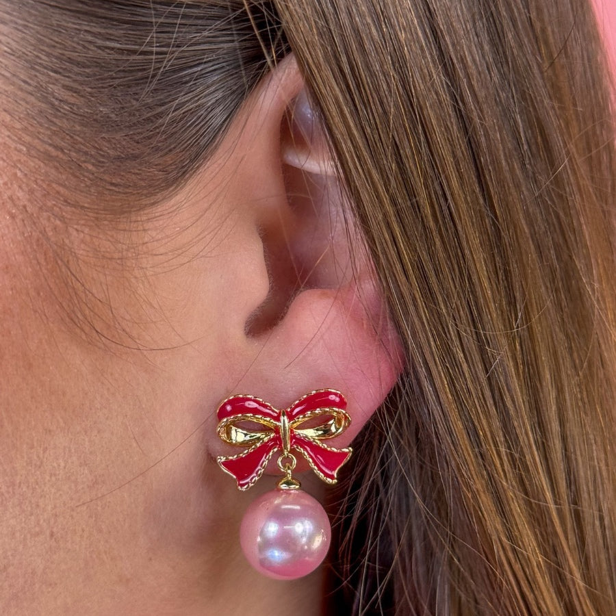 lightweight pink enamel bow stud trimmed in gold with a dangling iridescent pearl finished with a comfort disc backing