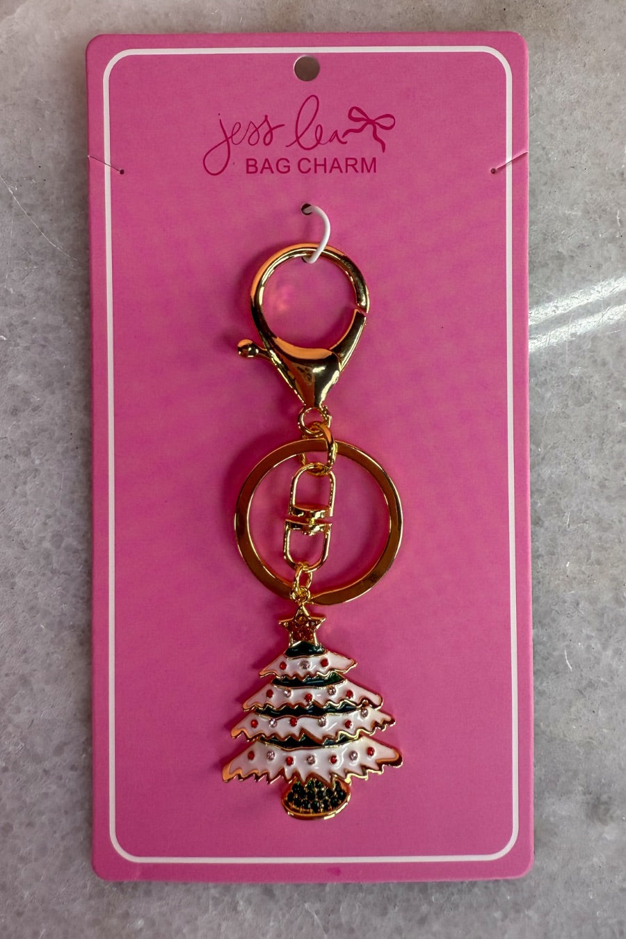 a festive layered green enamel fir Christmas tree with snowy white detailing, sprinkled with red and crystal accents, and crowned with a shimmering gold star, complete with a gold-tone swivel clasp and matching keyring