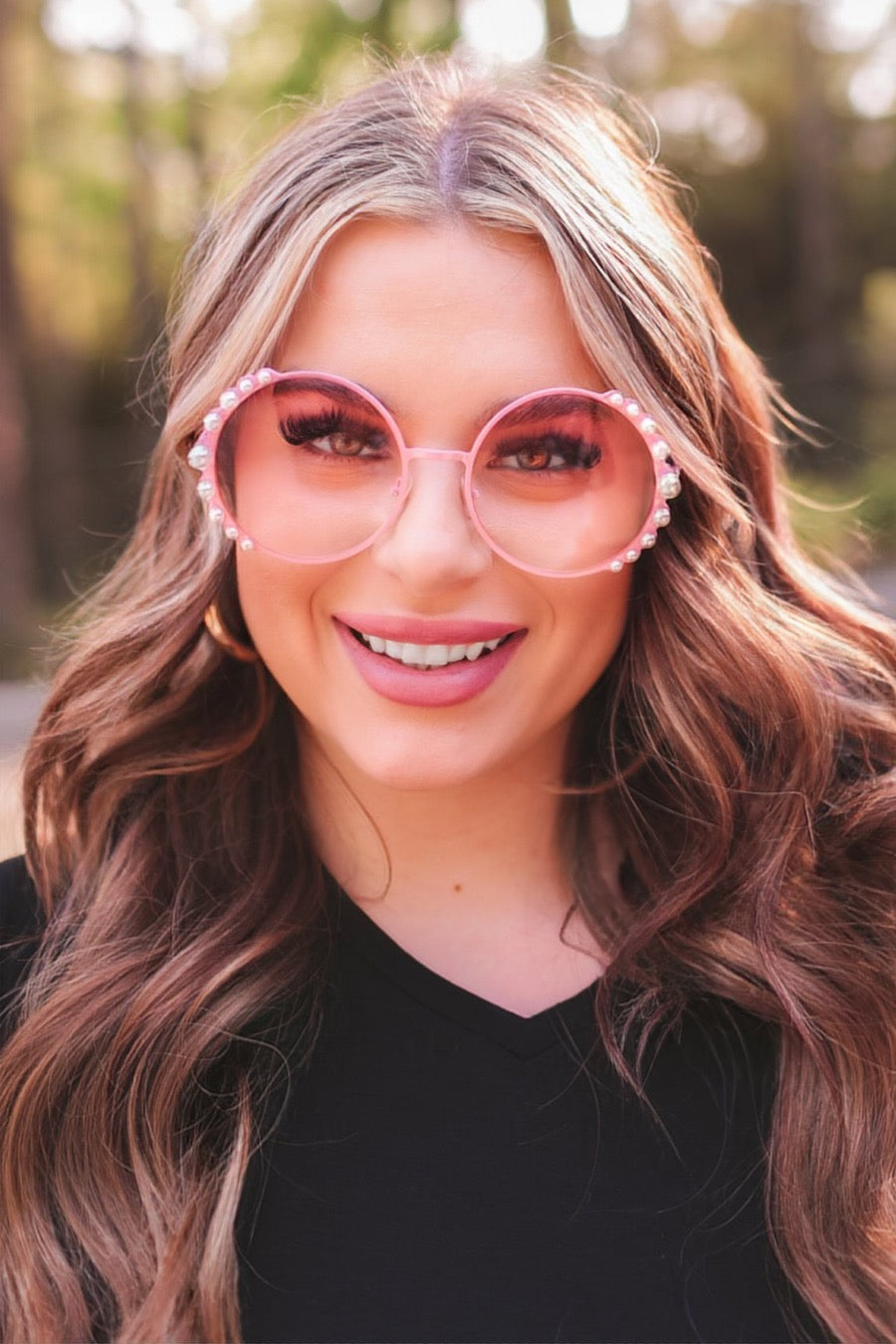 pink round sunglasses with scalloped edges and mixed-sized pearl trim around the frames, UV protection, and brand name detail (on both the temple and the complimentary black pouch)
