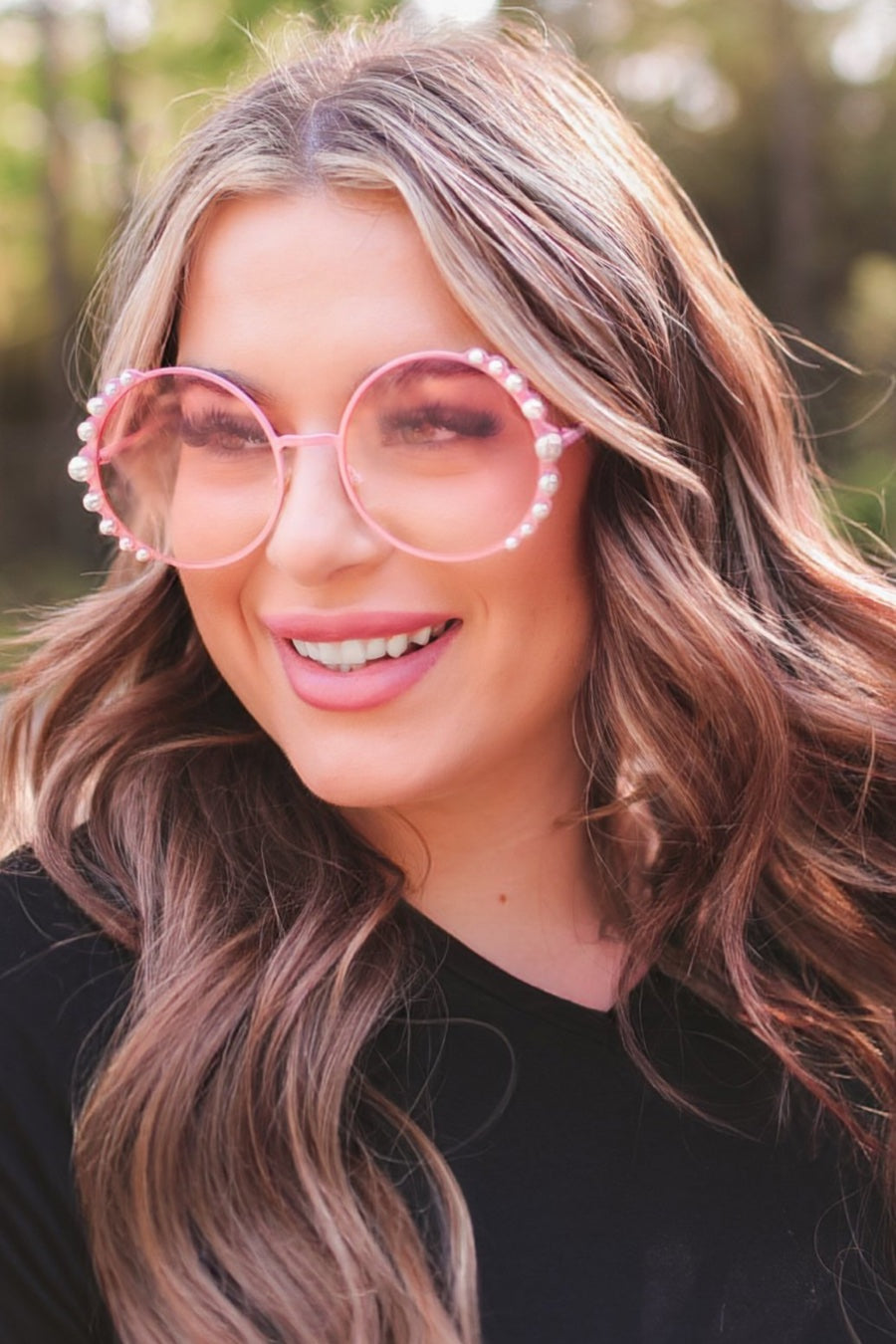 pink round sunglasses with scalloped edges and mixed-sized pearl trim around the frames, UV protection, and brand name detail (on both the temple and the complimentary black pouch)