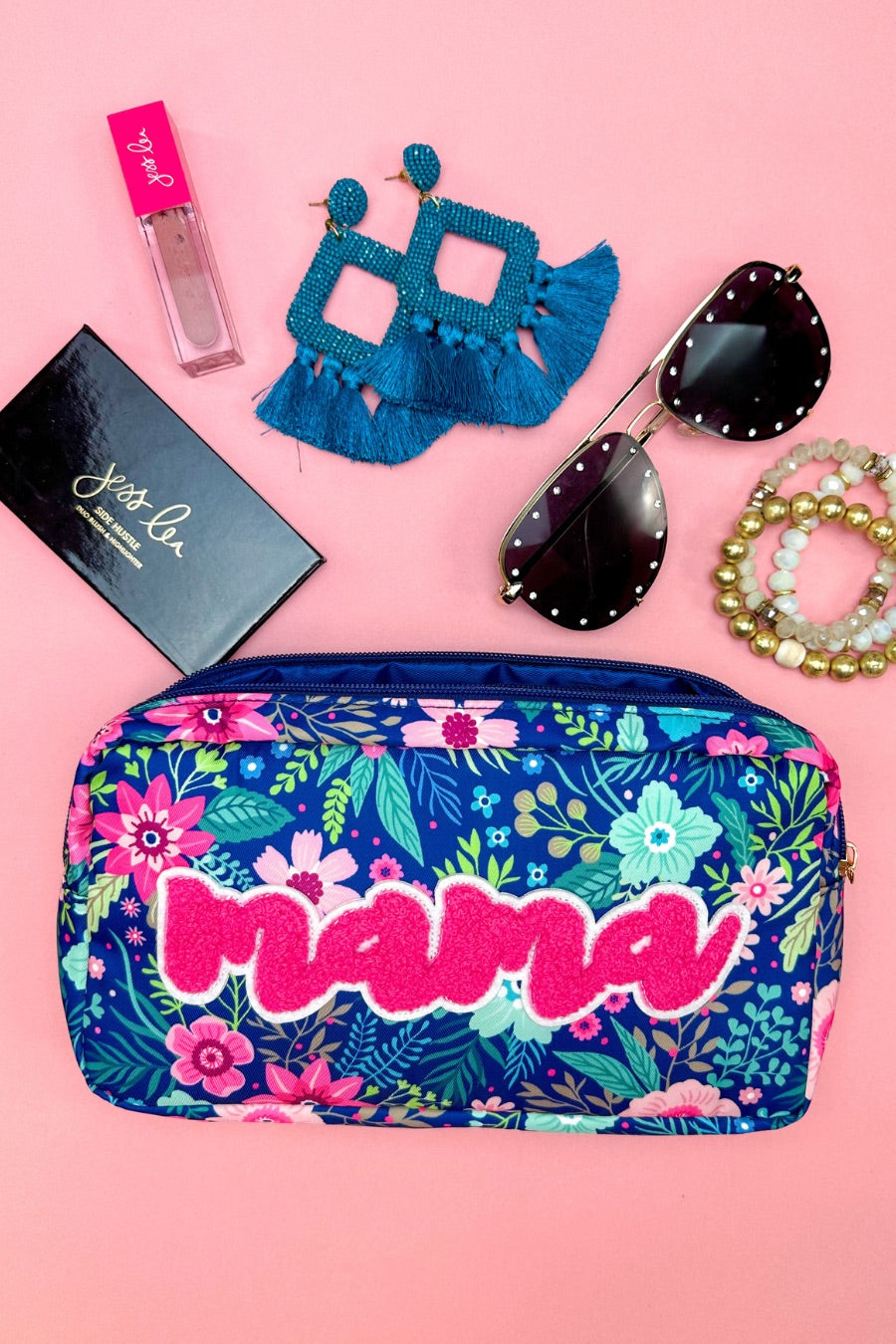 a lightweight spacious travel bag with a unique navy floral pattern (aqua, green, pink, and teal), a bold hot pink chenille 'mama' patch with white trim, and a zipper closer