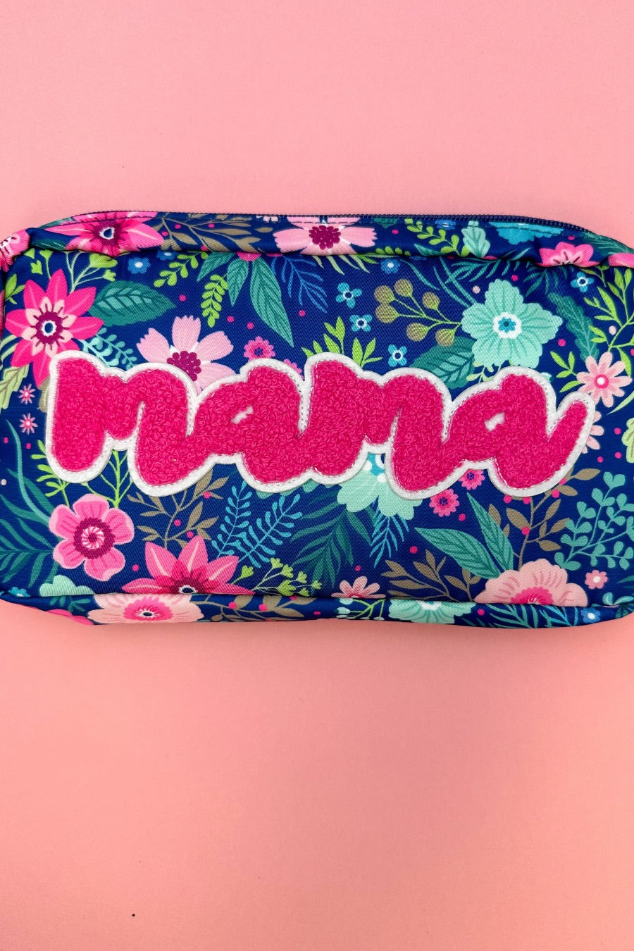 a lightweight spacious travel bag with a unique navy floral pattern (aqua, green, pink, and teal), a bold hot pink chenille 'mama' patch with white trim, and a zipper closer