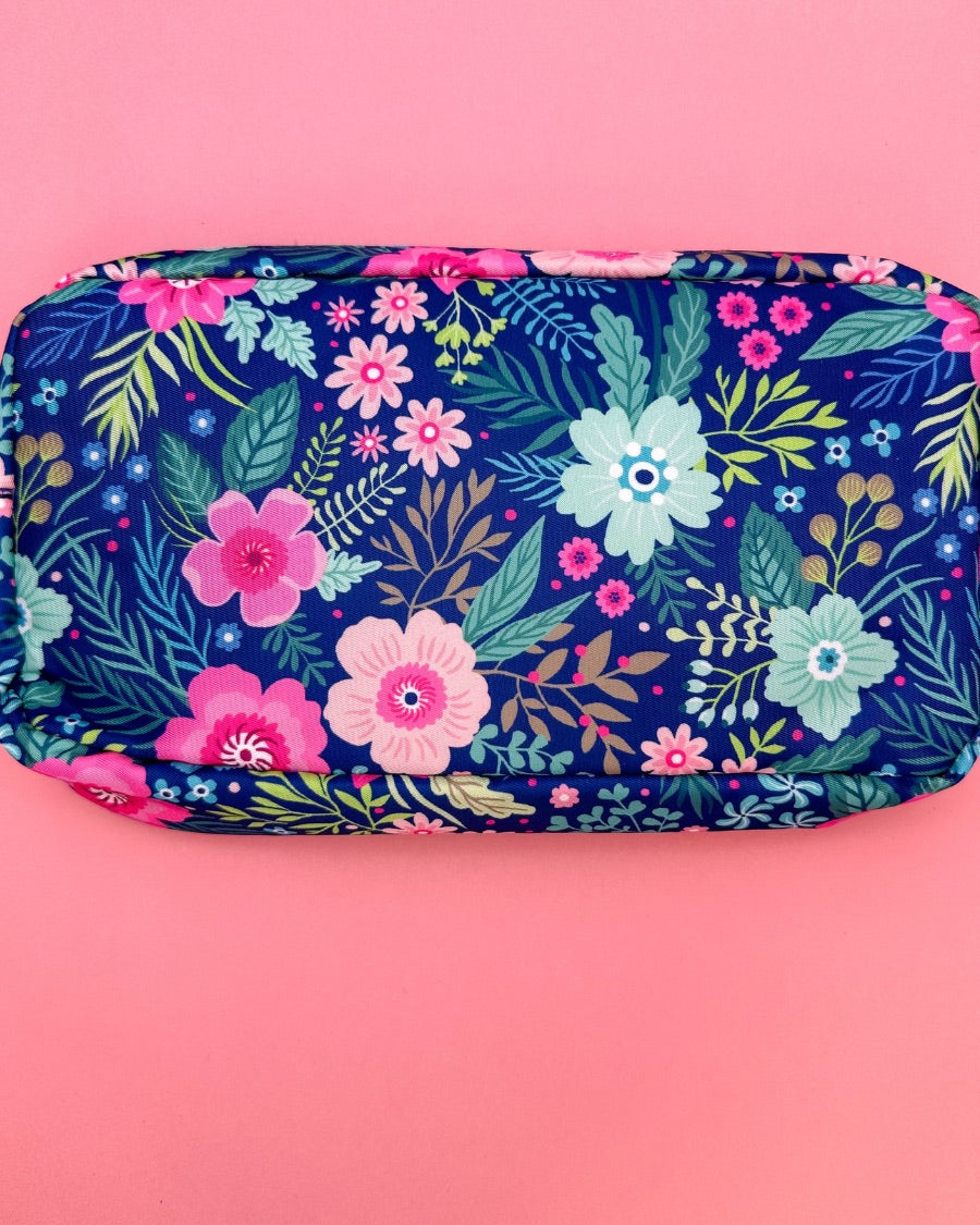 a lightweight spacious travel bag with a unique navy floral pattern (aqua, green, pink, and teal), a bold hot pink chenille 'mama' patch with white trim, and a zipper closer