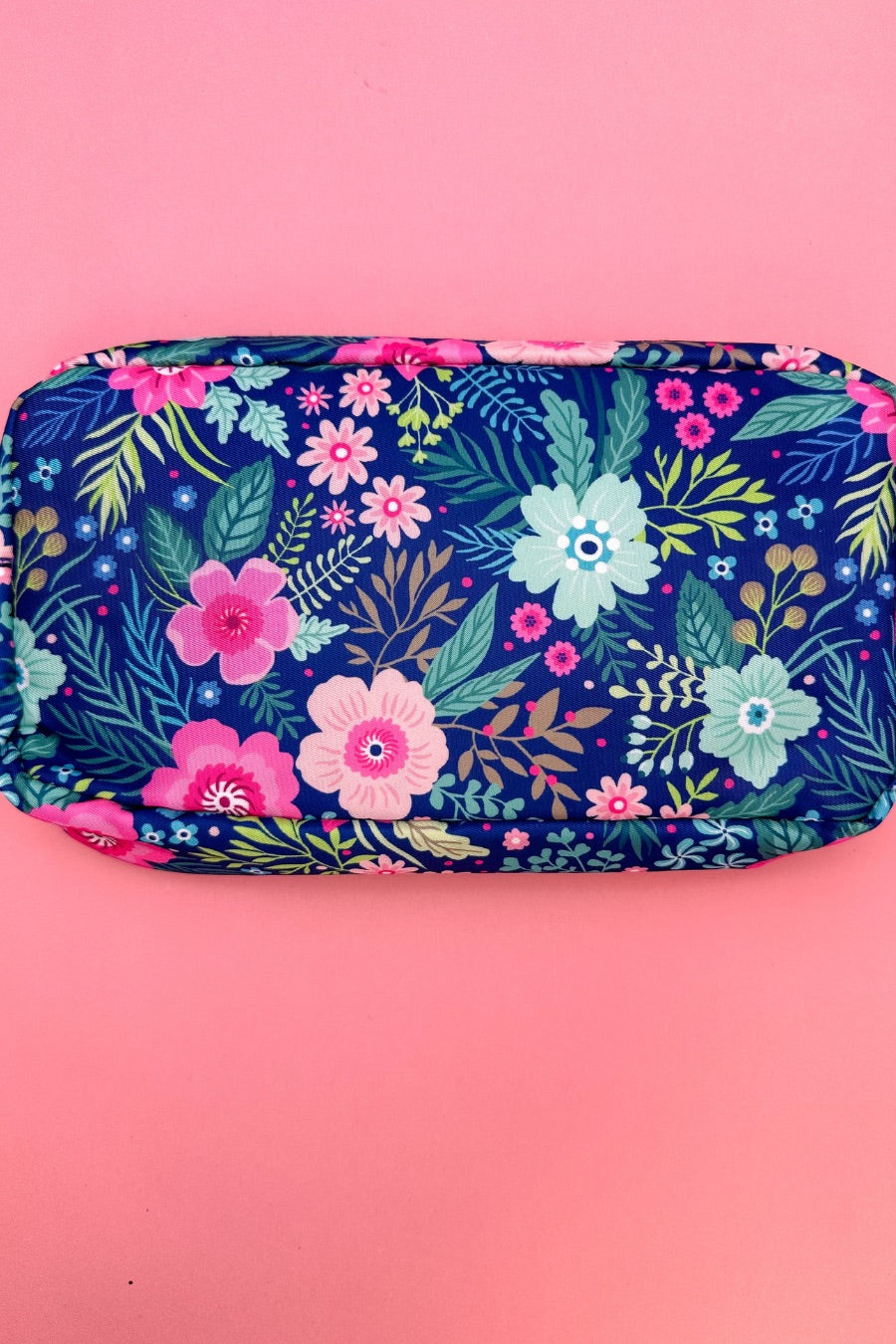 a lightweight spacious travel bag with a unique navy floral pattern (aqua, green, pink, and teal), a bold hot pink chenille 'mama' patch with white trim, and a zipper closer