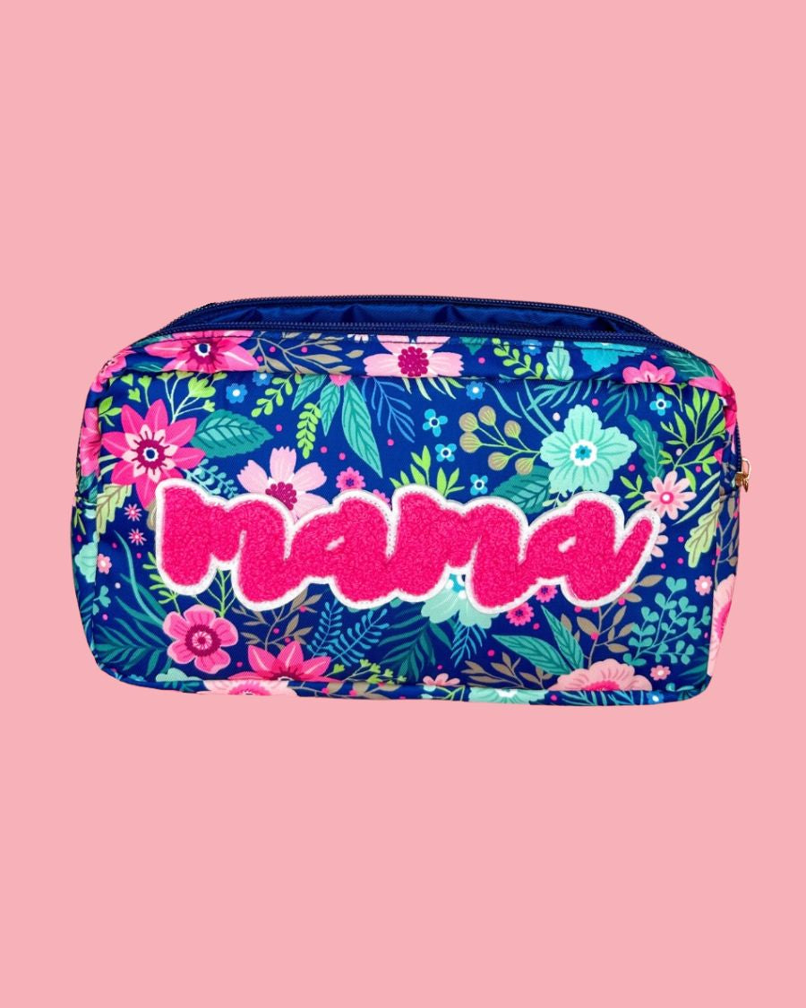 a lightweight spacious travel bag with a unique navy floral pattern (aqua, green, pink, and teal), a bold hot pink chenille 'mama' patch with white trim, and a zipper closer