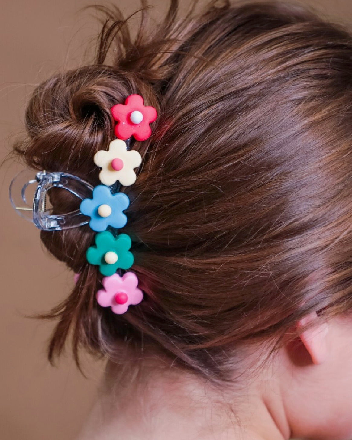 Multicolor flower-shaped hair clip in a bun against a neutral background