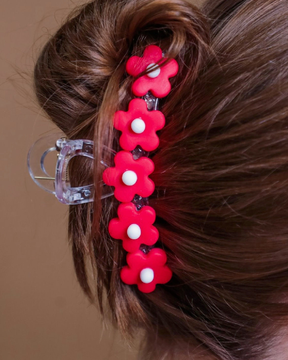 Red flower-shaped hair clip in a bun against a neutral background