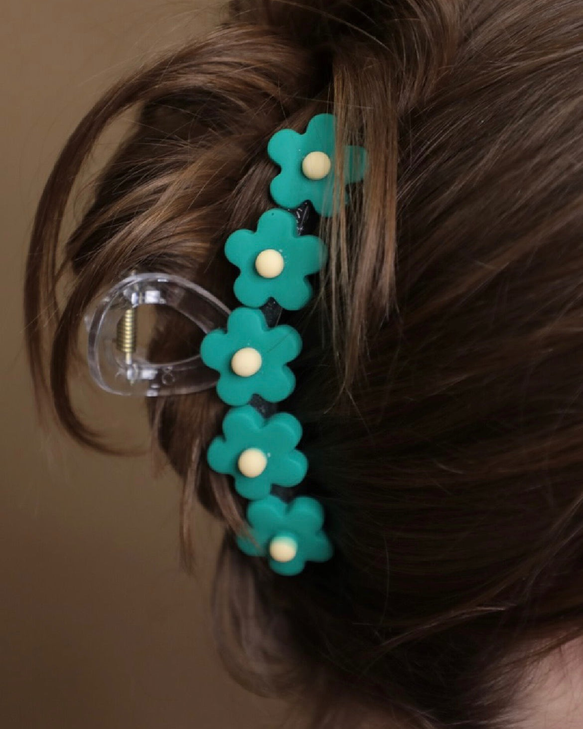 Teal flower-shaped hair clip in a bun against a neutral background