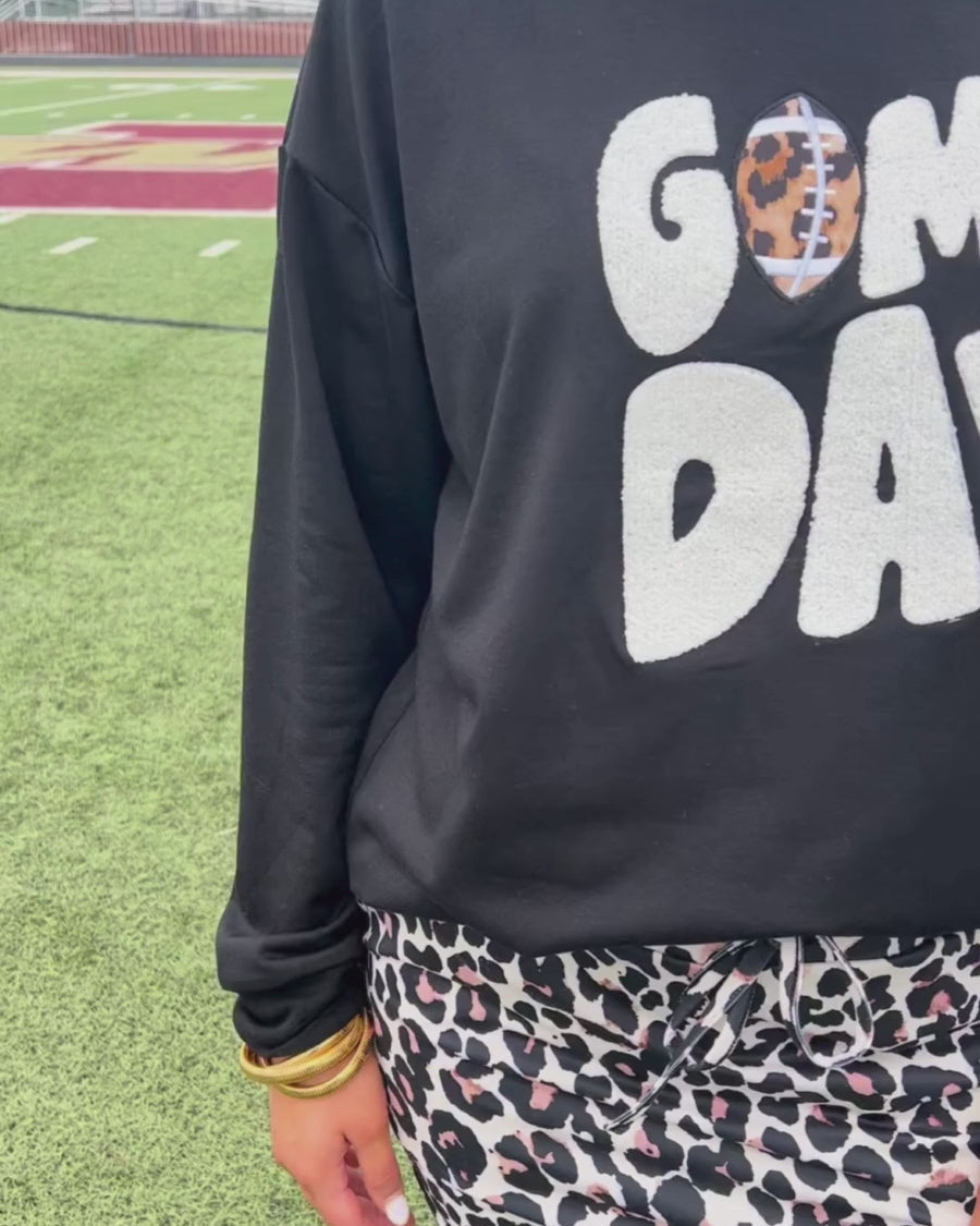 a black long-sleeve sweatshirt with standout "Game Day" chenille patch lettering in white and a leopard football detail as the A on an ultra-soft, midweight fabric