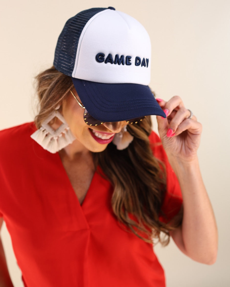a lightweight navy two-tone trucker hat with raised embroidered 'GAME DAY' lettering, tall foam front panel, breathable mesh back, snapback closure, and a curved bill