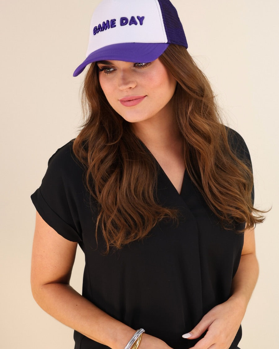 a lightweight purple two-tone trucker hat with raised embroidered 'GAME DAY' lettering, tall foam front panel, breathable mesh back, snapback closure, and a curved bill