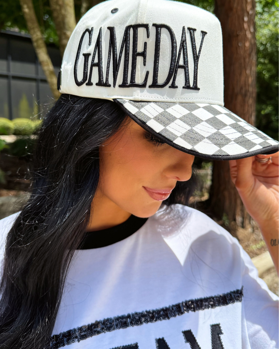 a neutral game day cap with bold embroidered lettering, a black-and-white checkered bill, contrast trim, and a sporty boutique-inspired design