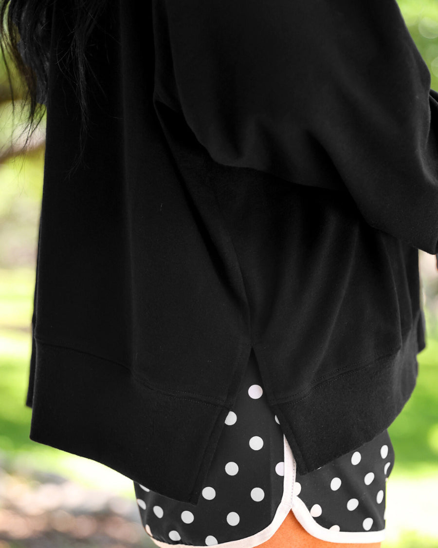 a relaxed black French terry pullover with a V-neckline, mixed polka dot and gingham 'GAME DAY' lettering, long sleeves, banded cuffs, and side slit hems on a cotton fabric