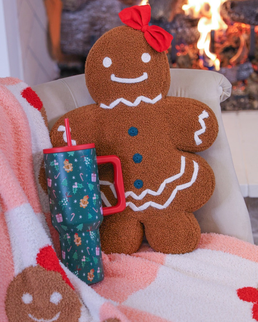 brown gingerbread girl fluffy pillow with dainty white icing details, stitched forest green buttons, and an adorable red bow with coordinating blanket and tumbler