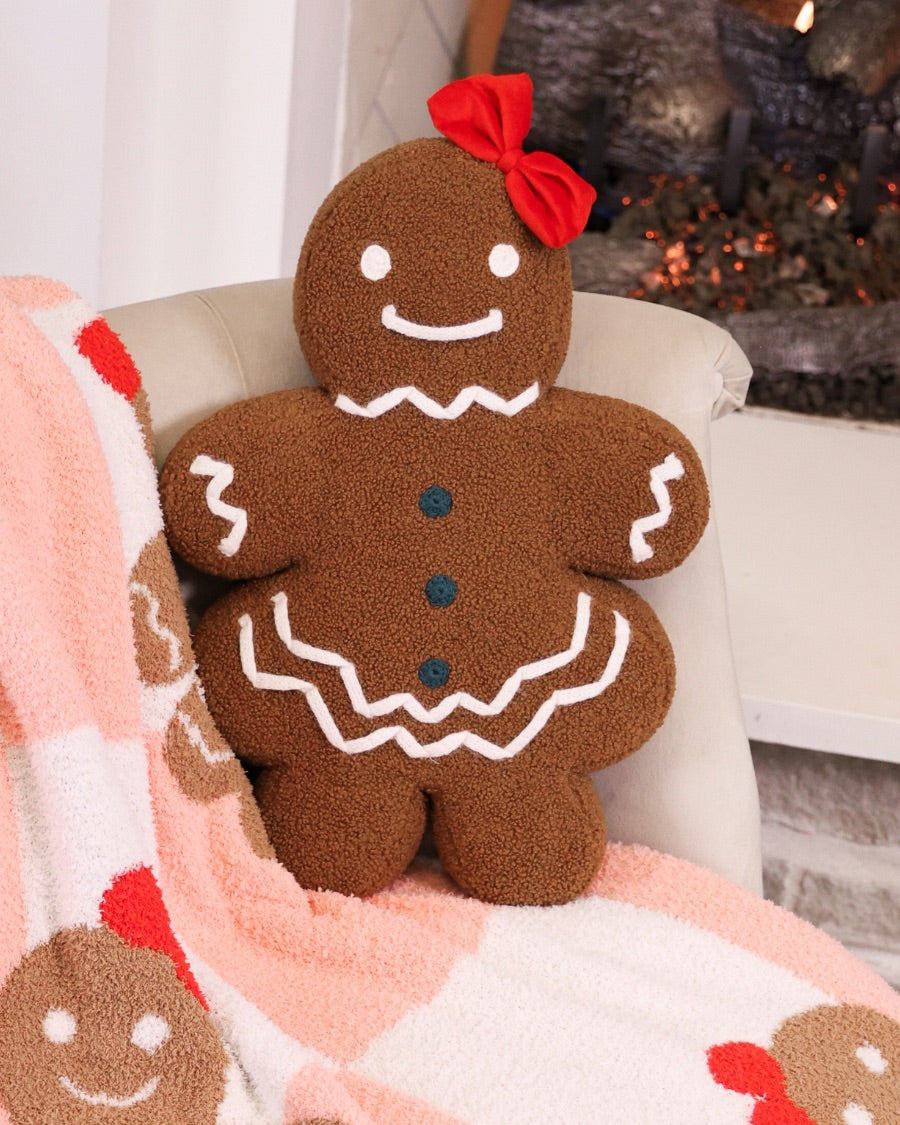 brown gingerbread girl fluffy pillow with dainty white icing details, stitched forest green buttons, and an adorable red bow paired with a coordinating blanket
