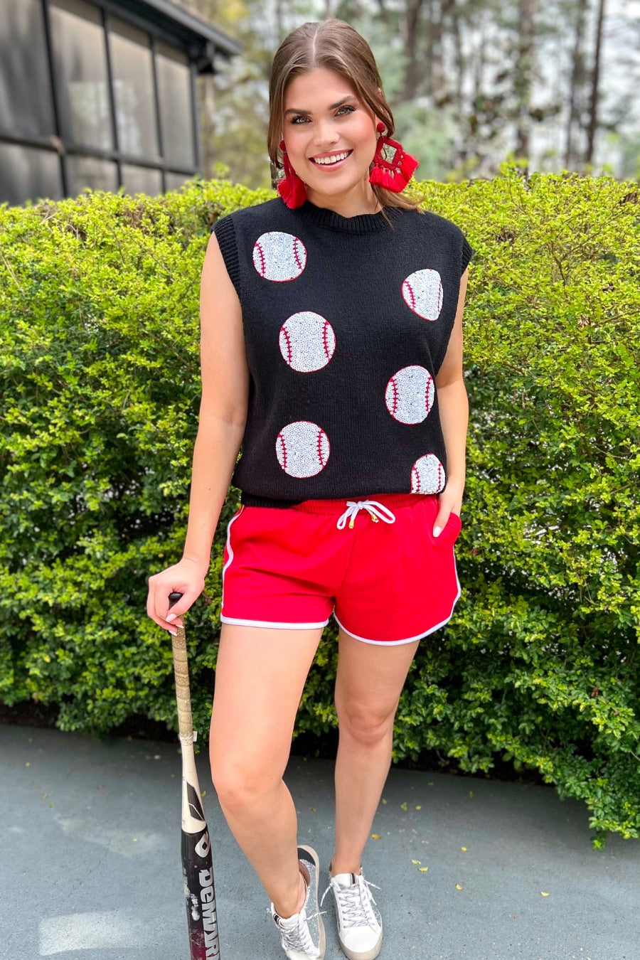 a black sleeveless sweater vest with an oversized fit, an allover textured baseball motif, and ribbed trim at the neckline, arm openings, and hem
