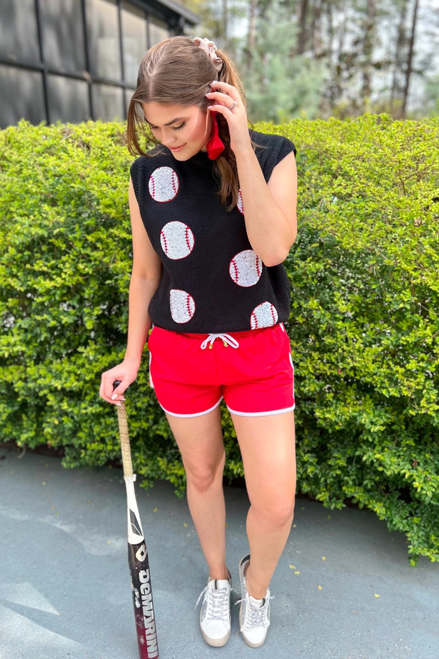 a black sleeveless sweater vest with an oversized fit, an allover textured baseball motif, and ribbed trim at the neckline, arm openings, and hem