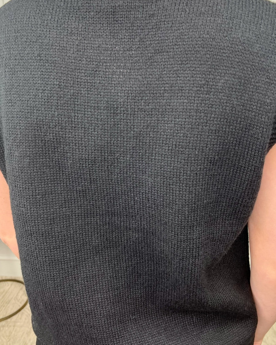 a black sleeveless sweater vest with an oversized fit, an allover textured baseball motif, and ribbed trim at the neckline, arm openings, and hem