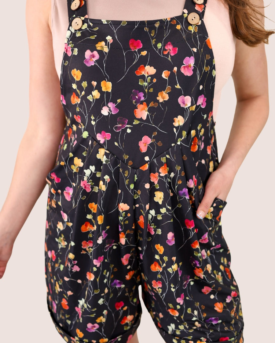 multicolor floral pattern print overall shorts on a black base made from our best-selling everyday fabric with functional button straps, cuffed hems, and side pockets