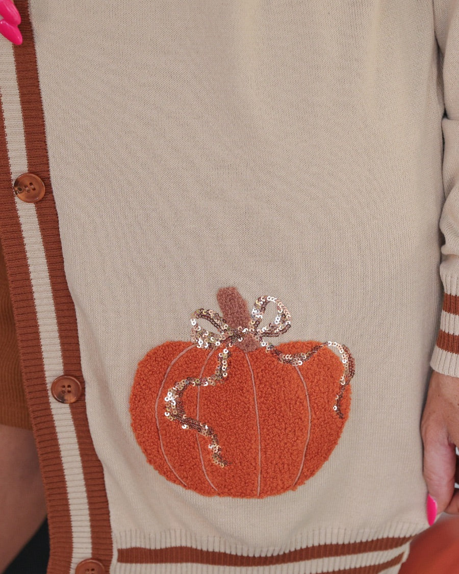 long-sleeve open front cardigan adorned with chenille pumpkins and sequin bows, functional pockets, and a relaxed fit in neutral