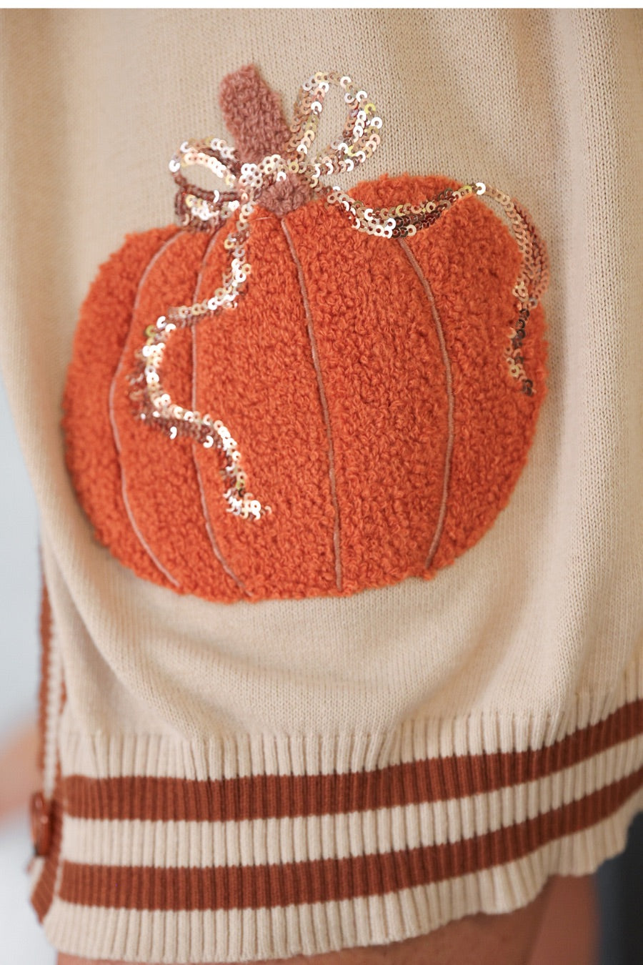 long-sleeve open front cardigan adorned with chenille pumpkins and sequin bows, functional pockets, and a relaxed fit in neutral
