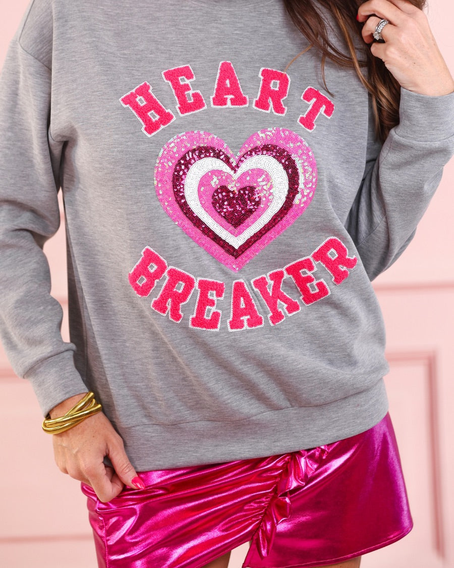 a gray long-sleeve pullover made from luxe material with chenille 'HEART BREAKER' lettering, a layered sequin heart detail, relaxed drop-shoulder fit, and ribbed neckline, cuffs, and hem for an effortlessly elevated look