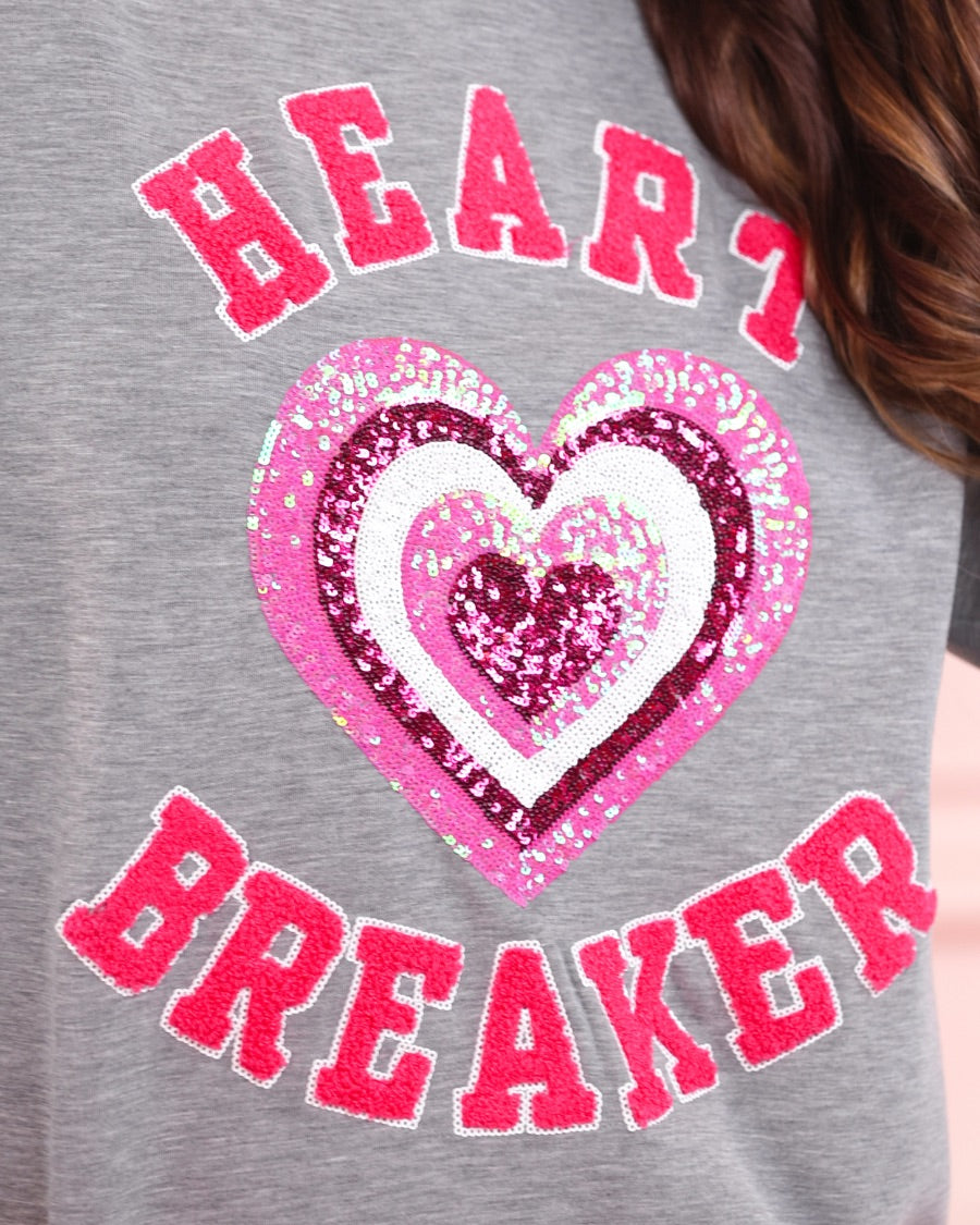 a gray long-sleeve pullover made from luxe material with chenille 'HEART BREAKER' lettering, a layered sequin heart detail, relaxed drop-shoulder fit, and ribbed neckline, cuffs, and hem for an effortlessly elevated look