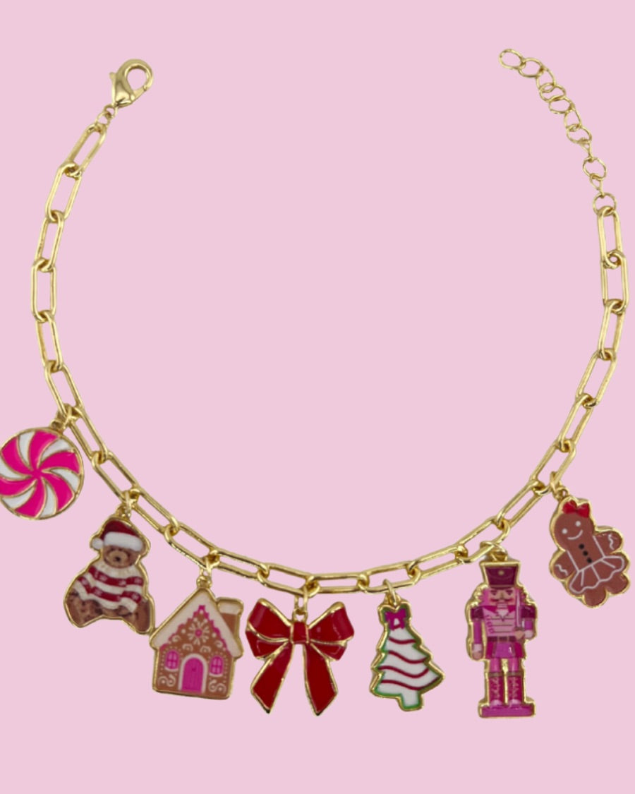 an adjustable gold link bracelet adorned with whimsical enamel charms (a bold red bow, Christmas bear, Christmas tree, gingerbread girl, gingerbread house, pink nutcracker, and a pink peppermint)