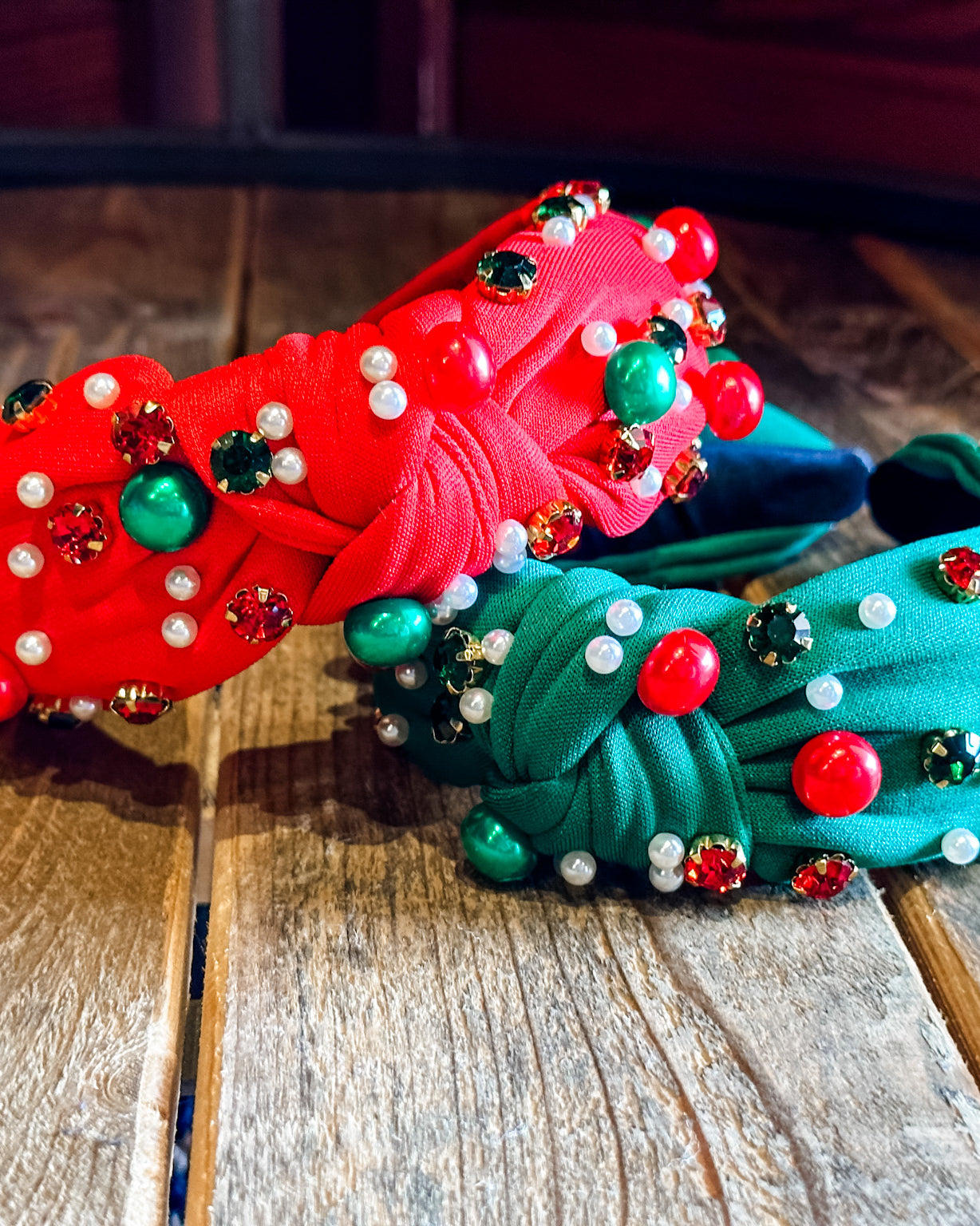 top knot adorned with jewel-tone beads, pearls, and rhinestones on velvet in green and red