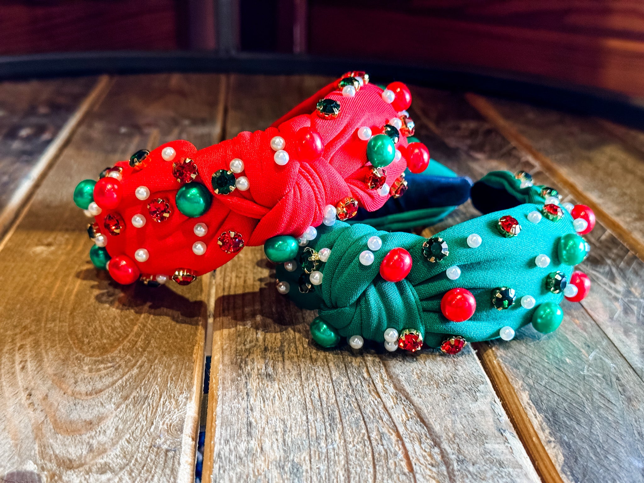 top knot adorned with jewel-tone beads, pearls, and rhinestones on velvet in green and red