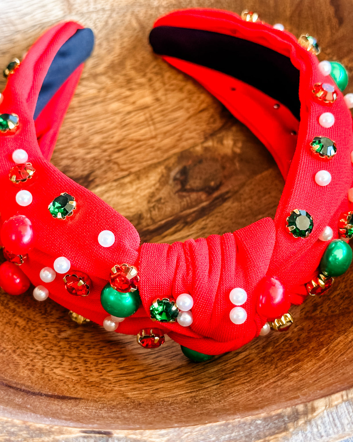 top knot adorned with jewel-tone beads, pearls, and rhinestones on velvet in red