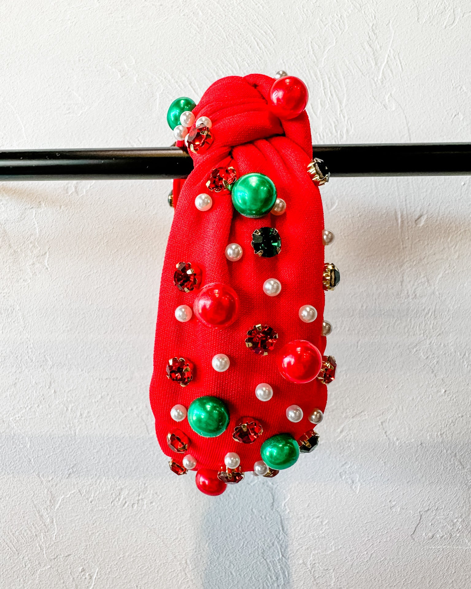 top knot adorned with jewel-tone beads, pearls, and rhinestones on velvet in red