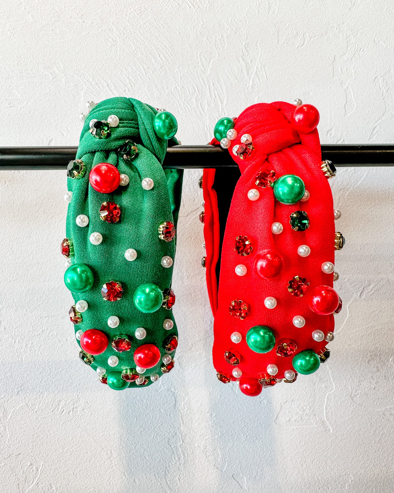 top knot adorned with jewel-tone beads, pearls, and rhinestones on velvet in green and red