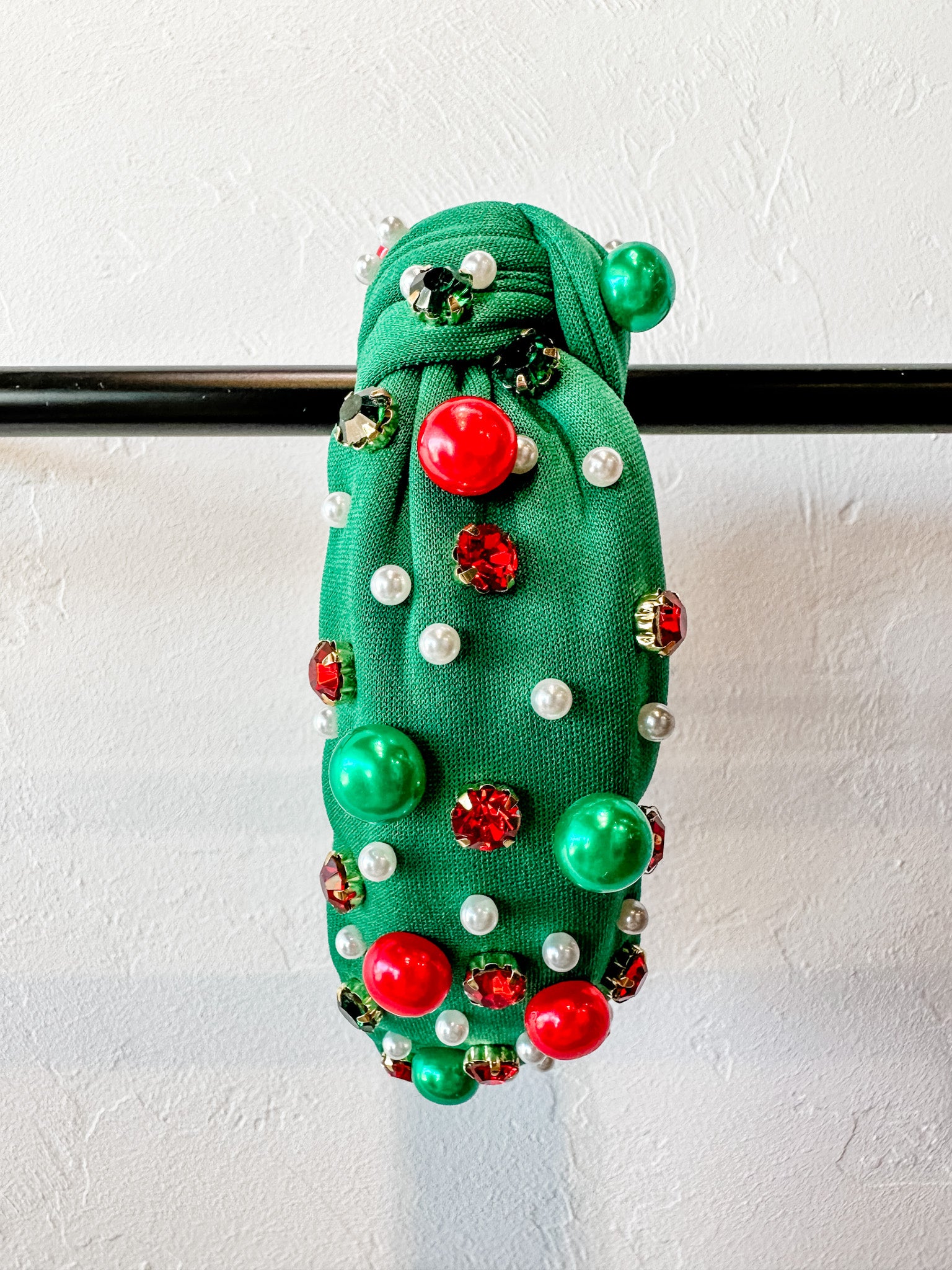 top knot adorned with jewel-tone beads, pearls, and rhinestones on velvet in green