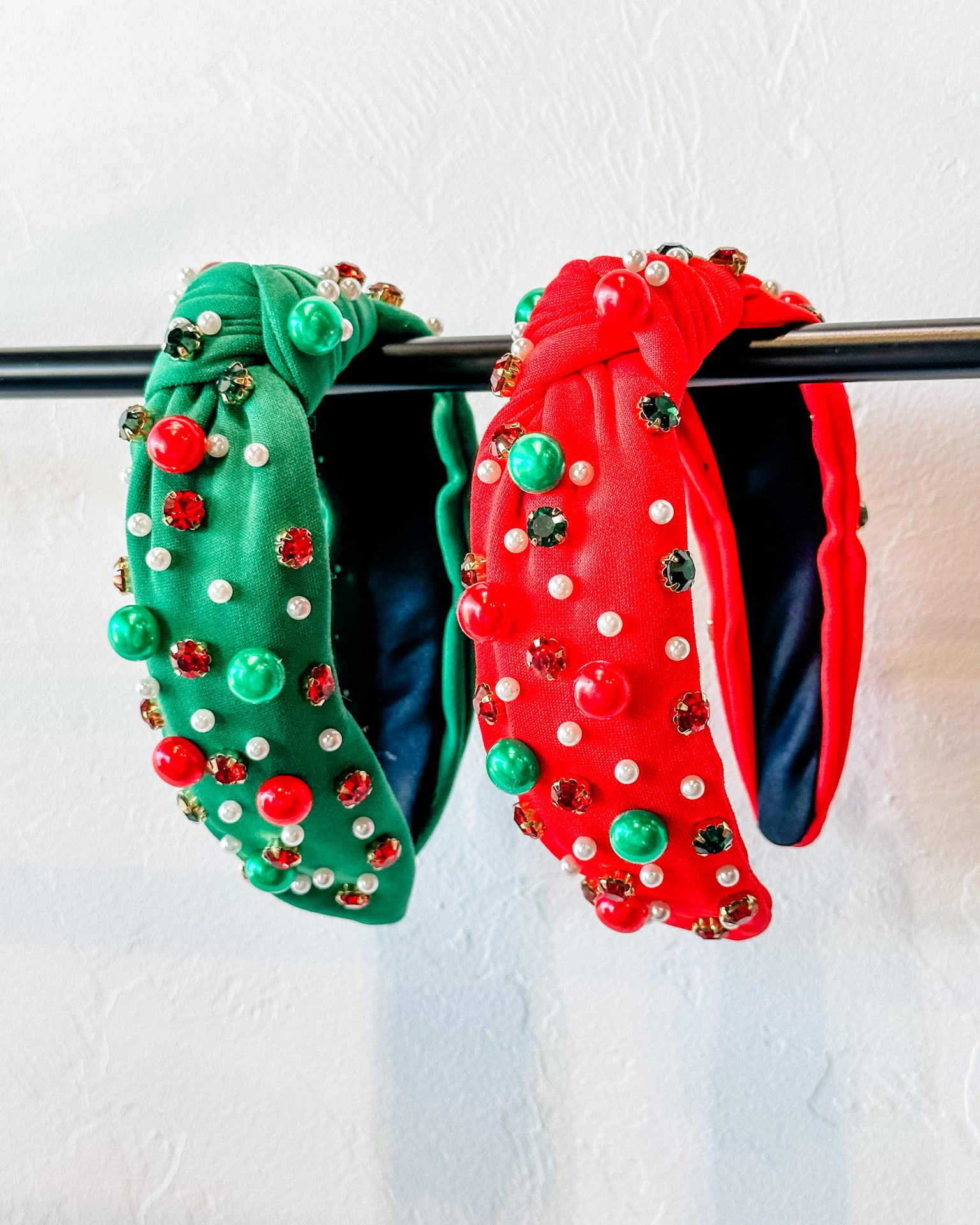 top knot adorned with jewel-tone beads, pearls, and rhinestones on velvet in green and red