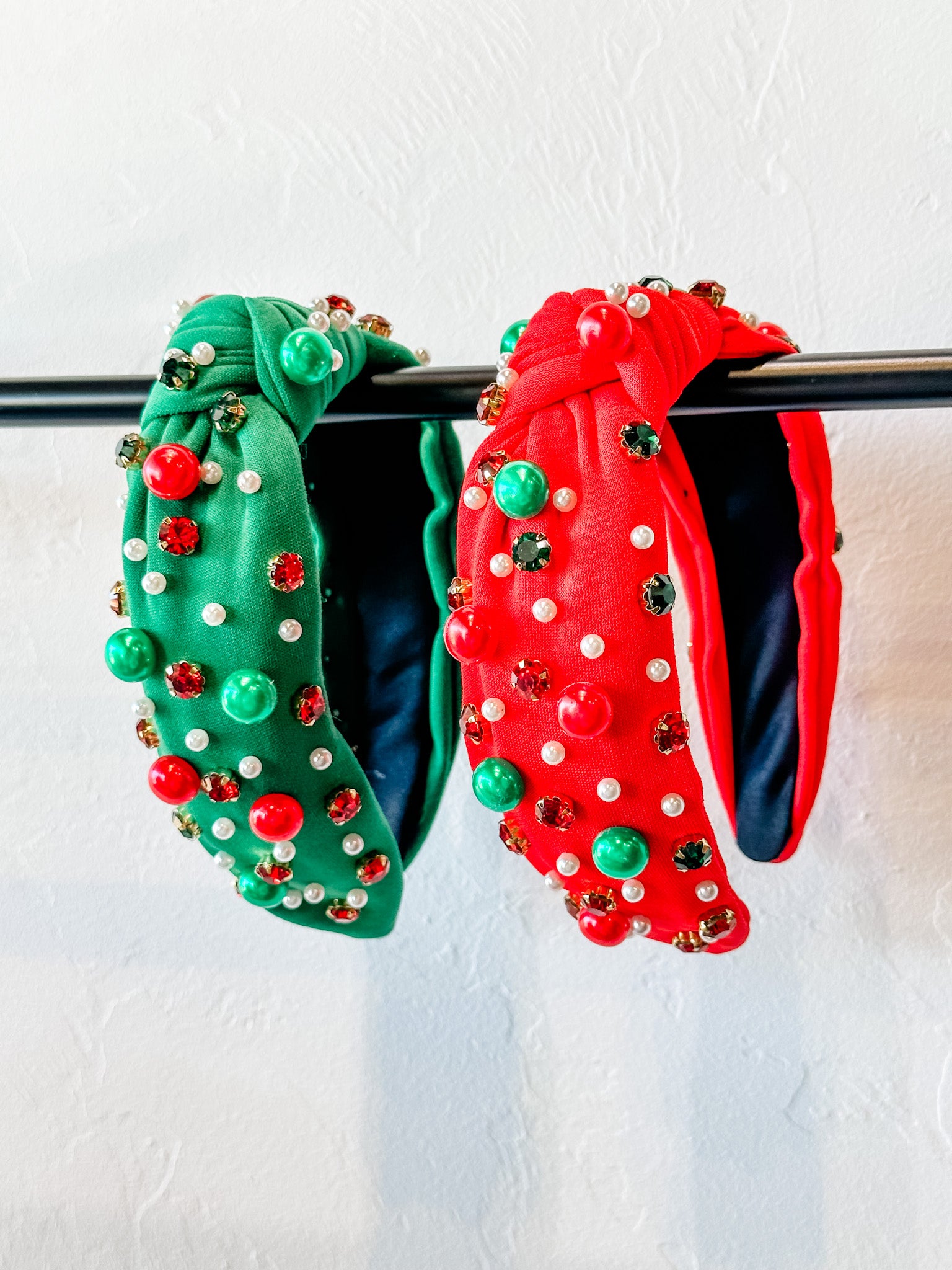 top knot adorned with jewel-tone beads, pearls, and rhinestones on velvet in green and red