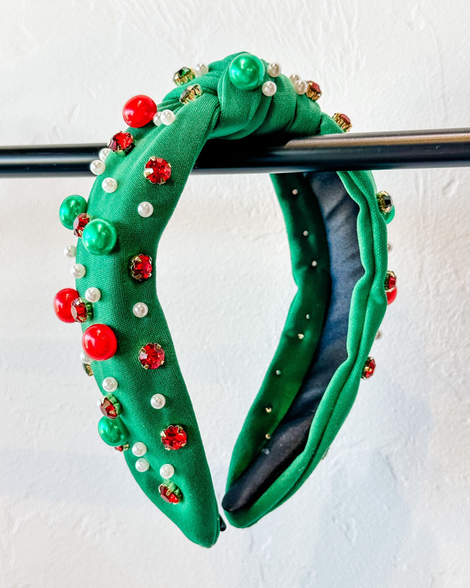 top knot adorned with jewel-tone beads, pearls, and rhinestones on velvet in green