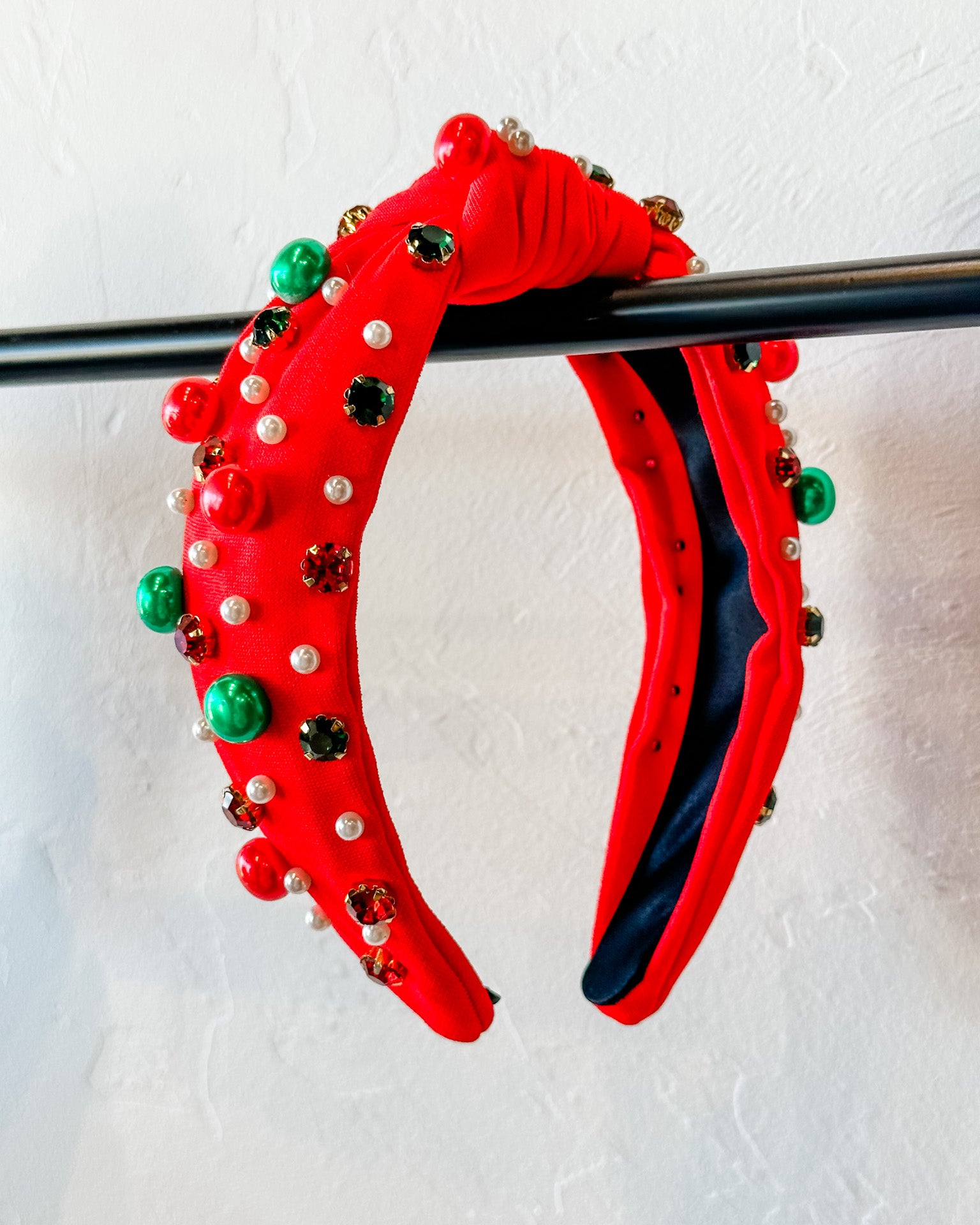 top knot adorned with jewel-tone beads, pearls, and rhinestones on velvet in red