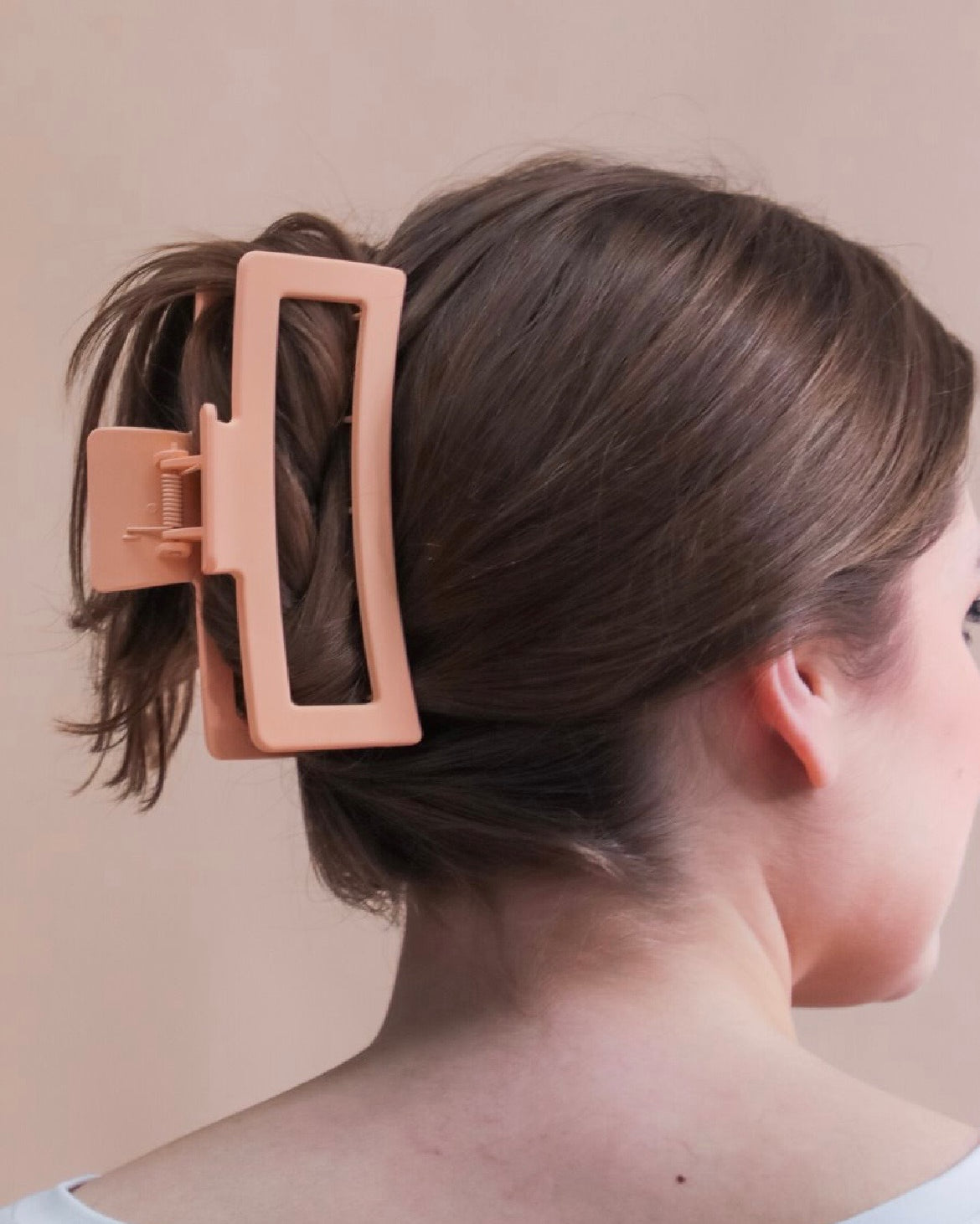 Close-up of a person's hair with a peach hair clip.