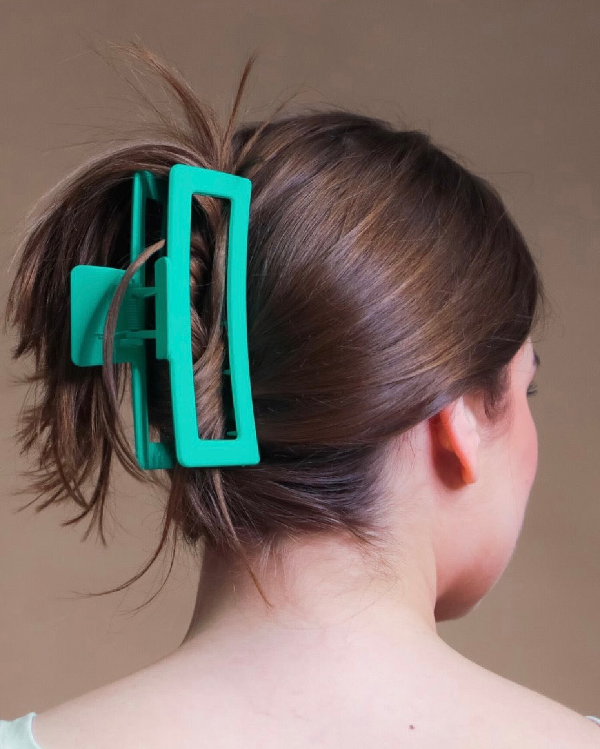 Close-up of a person's hair with a teal hair clip.
