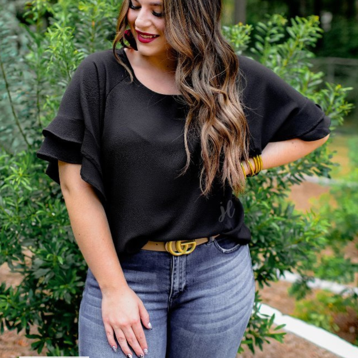 a black true-to-size blouse crafted from lightweight textured fabric with a rounded neckline, tiered ruffle sleeves, and a relaxed drape, accented by a MADE IN USA watermark in the bottom left-hand corner