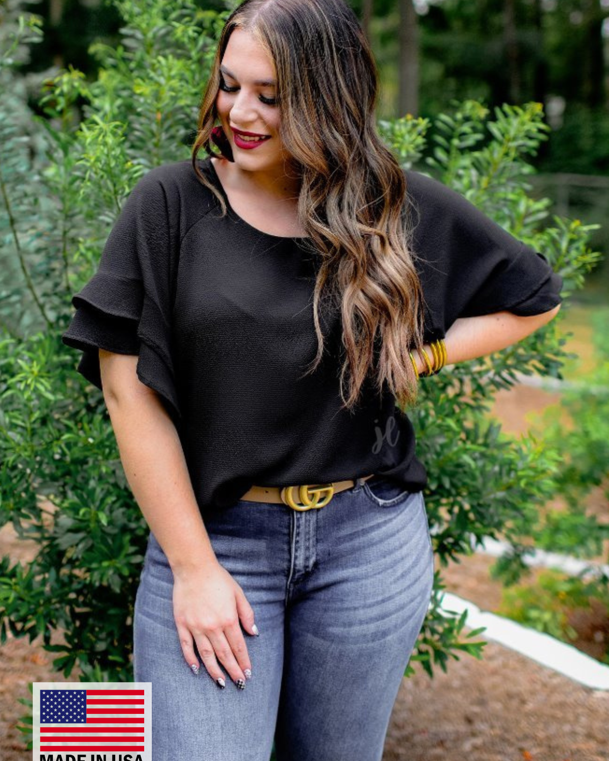a black true-to-size blouse crafted from lightweight textured fabric with a rounded neckline, tiered ruffle sleeves, and a relaxed drape, accented by a MADE IN USA watermark in the bottom left-hand corner