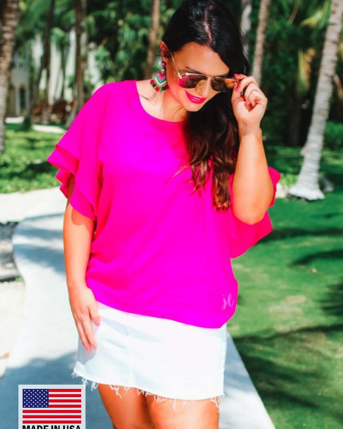 a pink true-to-size blouse crafted from lightweight textured fabric with a rounded neckline, tiered ruffle sleeves, and a relaxed drape, accented by a MADE IN USA watermark in the bottom left-hand corner