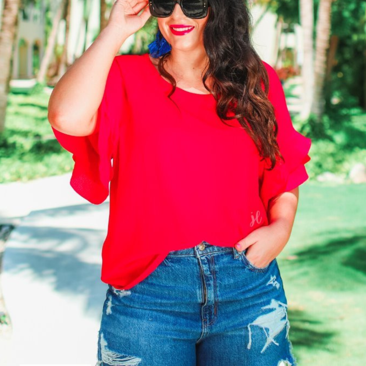 a red true-to-size blouse crafted from lightweight textured fabric with a rounded neckline, tiered ruffle sleeves, and a relaxed drape, accented by a MADE IN USA watermark in the bottom left-hand corner