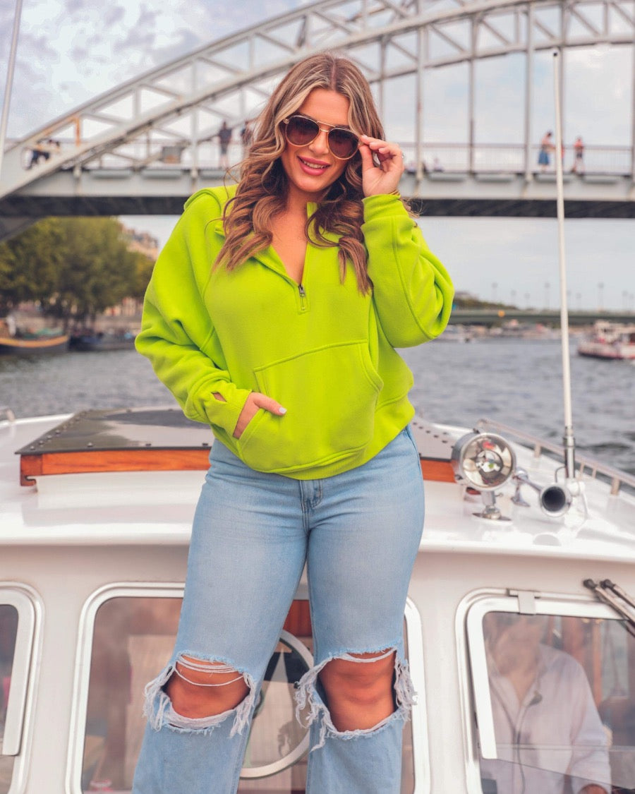 a cropped hooded quarter zip pullover with a relaxed fit, functional kangaroo pocket, and thumb holes in neon lime