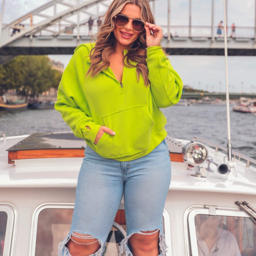 a cropped hooded quarter zip pullover with a relaxed fit, functional kangaroo pocket, and thumb holes in neon lime