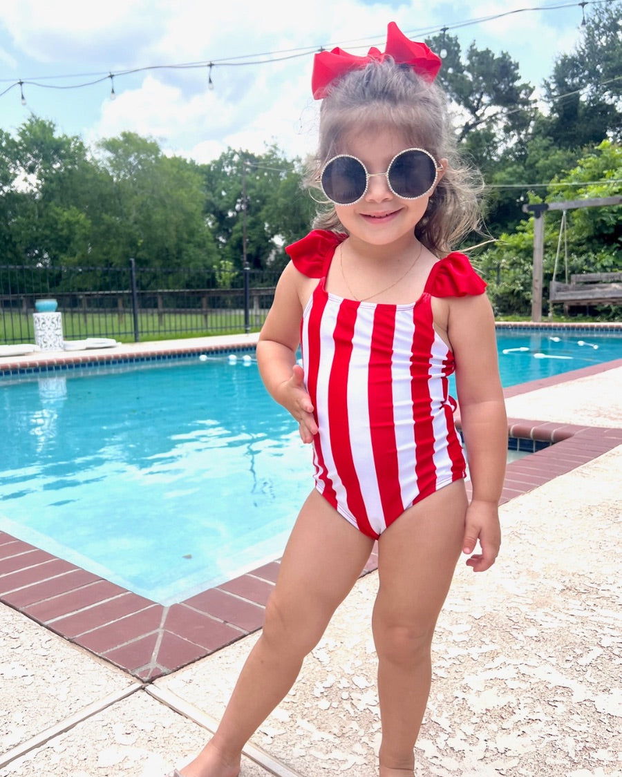 kids' sunglasses with rose gold frame and bridge, black round lenses, rhinestone trim, black temple tips featuring the brand name in white, nose pads, UV protection, and a signature pouch