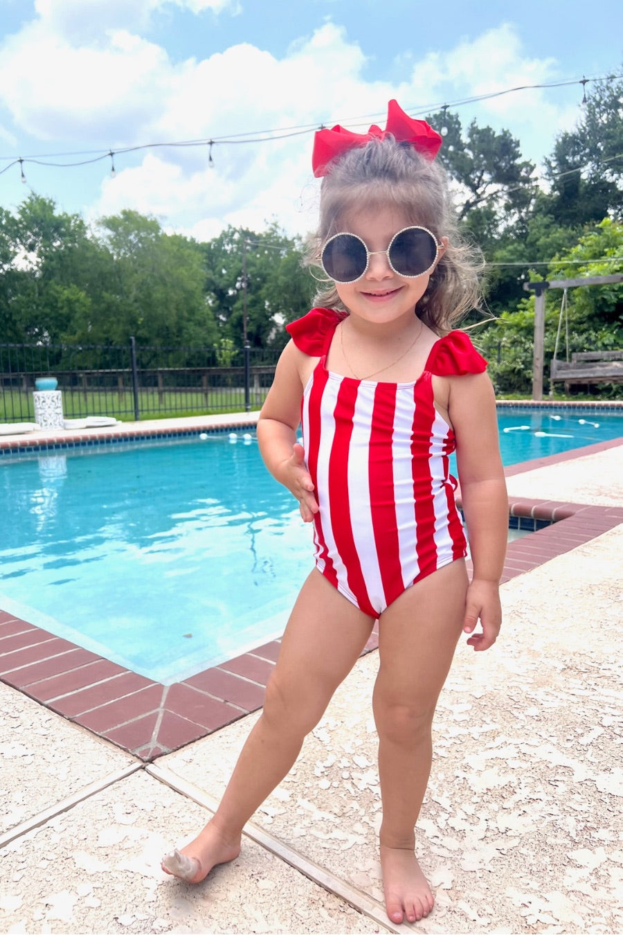 kids' sunglasses with rose gold frame and bridge, black round lenses, rhinestone trim, black temple tips featuring the brand name in white, nose pads, UV protection, and a signature pouch