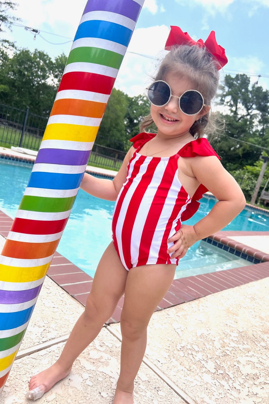 kids' sunglasses with rose gold frame and bridge, black round lenses, rhinestone trim, black temple tips featuring the brand name in white, nose pads, UV protection, and a signature pouch